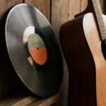 Piringan vinil dan gitar akustik bersandar di dinding kayu, suasana nostalgik dangdut lawas