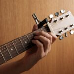 Close-up neck gitar akustik dengan capo terpasang di fret