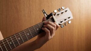 Close-up neck gitar akustik dengan capo terpasang di fret